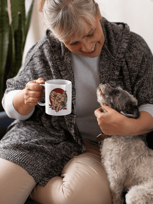 Old woman holding a Rose Jane Designs Cerberus Mug in one hand while looking at her dog