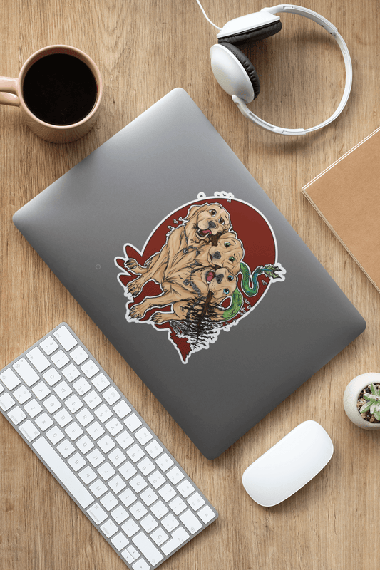 Laptop with a Rose Jane Designs Cerberus sticker on it. Next to headphones a mug, a mouse and a keyboard